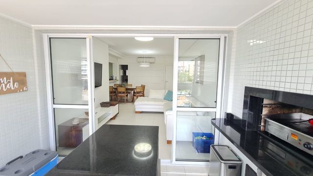 Os ambientes integrados, unindo sala, cozinha e sacada em um espaço harmonioso.