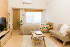 quarto com uma cama de casal paredes brancas janela com cortina e porta de madeira