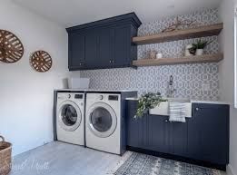 lavanderia ampla com paredes branca duas maquinas de lavar armarios azul de madeira