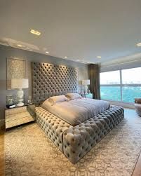 Quarto amplo com paredes cinza e cama de casal sacada de vidro frente mar