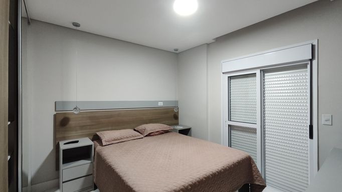 Outro ângulo da suíte, destacando conforto e iluminação.