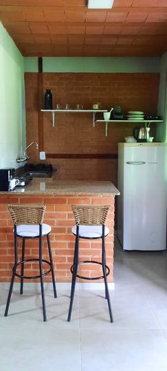 cozinha americana com balcão e sala de jantar mais geladeira, banquinhos para cozinha americana