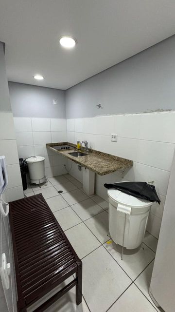 Cozinha de apoio equipada para suporte ao salão de festas, com bancada em granito, pia e área funcional para preparo e organização de eventos.