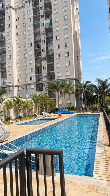 Piscina adulto com deck e área de descanso no condomínio.