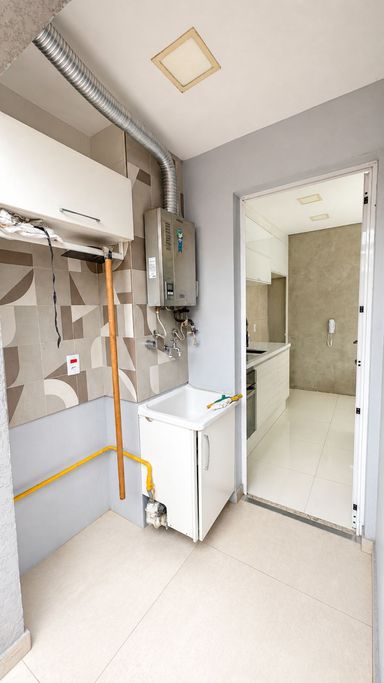 Área de serviço com tanque, aquecedor a gás e ventilação natural.
