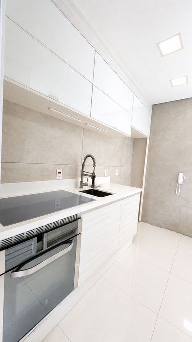 Cozinha planejada com armários superiores, bancada e cooktop por indução.
