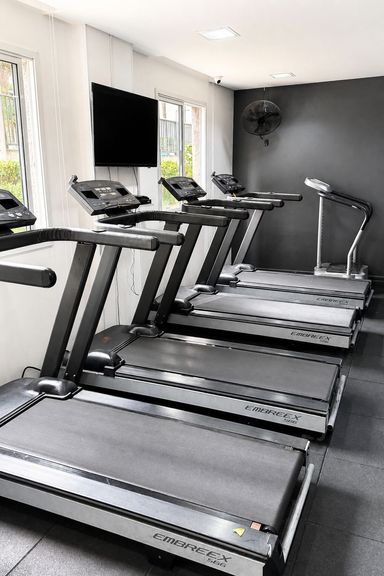 Sala fitness com esteiras e equipamentos para exercícios cardiovasculares.