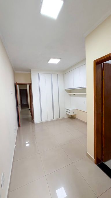 Suíte com amplos móveis planejados, módulos superiores, espaço para cama e iluminação completa em LED.