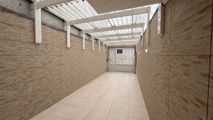 Garagem ampla e coberta, com estrutura de madeira, cobertura translúcida e paredes totalmente revestidas em cerâmica.