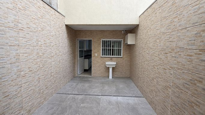 Lavanderia ventilada, com tanque, espaço para máquina de lavar e paredes totalmente revestidas em cerâmica.