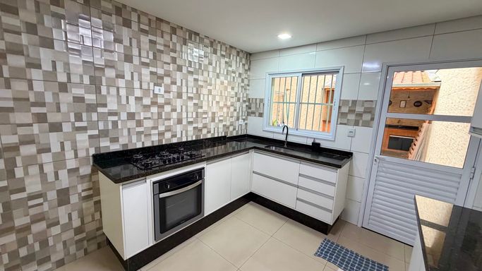 Cozinha planejada em formato funcional, com bancada em L, ótima circulação e iluminação natural proporcionada pela porta e janela.