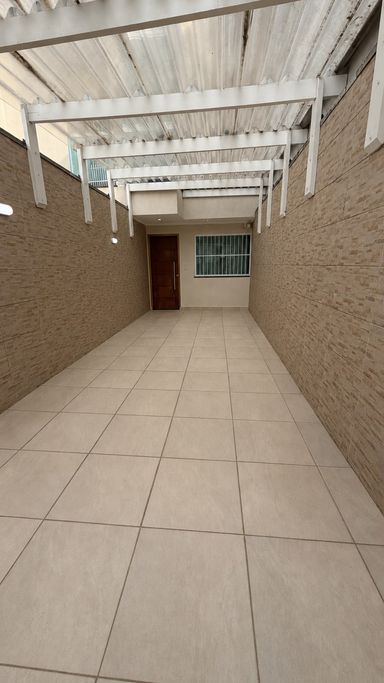 Garagem com portão automático, entrada independente para pedestres, iluminação em LED e paredes revestidas em cerâmica.