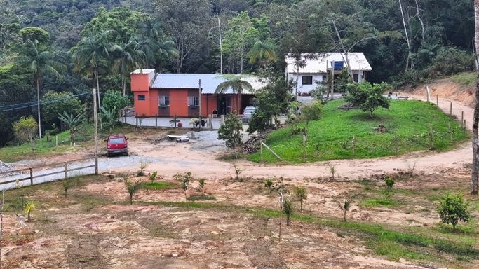Casas e jardim vistos do pátio no sítio à venda em Águas Mornas SC