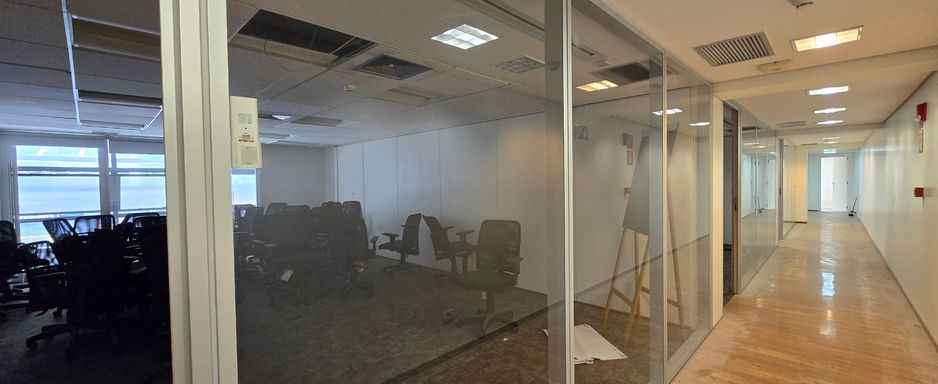 Circulação e salas delimitadas por divisórias de vidro.
