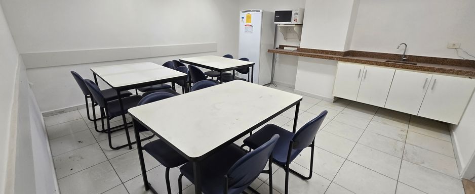 Refeitório com mesas, cadeiras e armários.