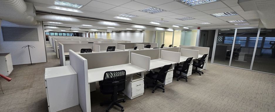 Estações de trabalho com divisórias e cadeiras.