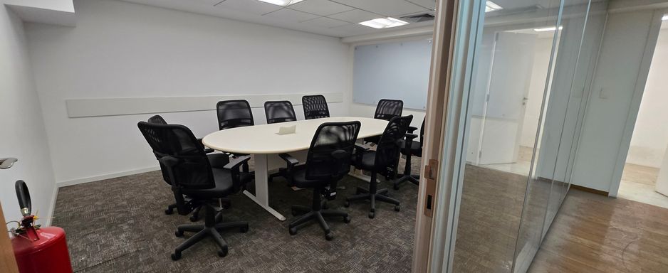 Sala de reunião com mesa e cadeiras.