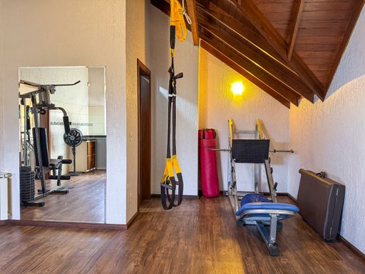 Salão de festas interno com churrasqueira e equipamentos de academia