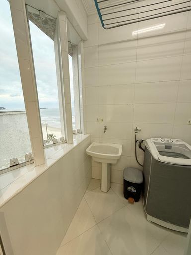 Lavanderia com vista mar, máquina de lavar roupa e armário