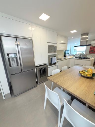 Cozinha integrada a sala de janatar com copa, repleto de armários e mesa com 4 cadeiras