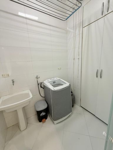 Lavanderia com vista mar, máquina de lavar roupa e armário