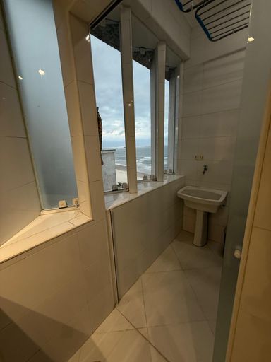Lavanderia com vista mar, máquina de lavar roupa e armário