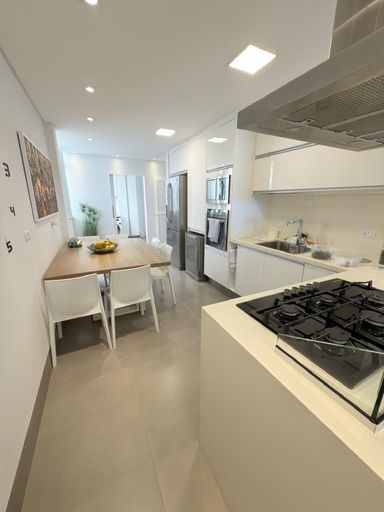 Cozinha integrada a sala de janatar com copa, repleto de armários e mesa com 4 cadeiras