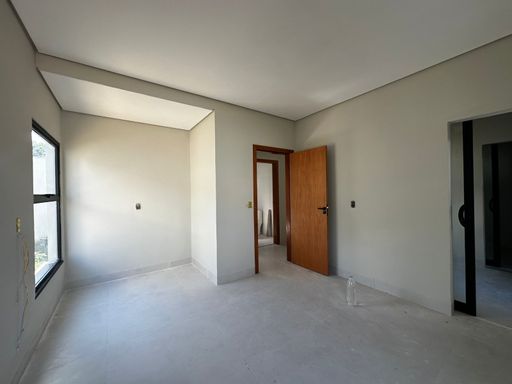 Amplo hall de circulação íntima ou antessala conectando os dormitórios, exibindo porta de passagem em madeira semi-oca envernizada, paginação uniforme de piso e teto rebaixado no Bairro Triângulo, em Porto Velho-RO.