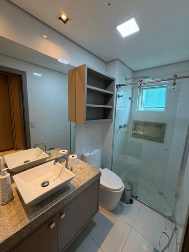 Banheiro completo com planejados, bancada em granito e box em vidro, acabamento moderno em apartamento de alto padrão.