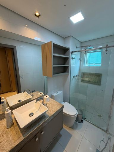 Banheiro completo com móveis planejados, bancada em granito e box em vidro, acabamento de alto padrão.