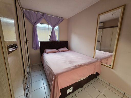 Quarto do imóvel no Condomínio Dália, bairro Novo em Porto Velho, com cama de casal, janela e armários.