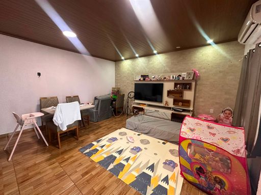 Sala de estar com sofá, mesa de jantar, piso amadeirado e tv.