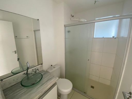 Banheiro do apartamento no Condomínio Vita Bella Porto Velho RO, com box de vidro, pia com bancada e revestimento cerâmico.
