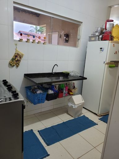 Detalhe da bancada técnica de pia suspensa em granito escuro com torneira fixada na parede e prateleira aramada inferior para organização de utensílios no Bairro Aeroclube, em Porto Velho-RO.