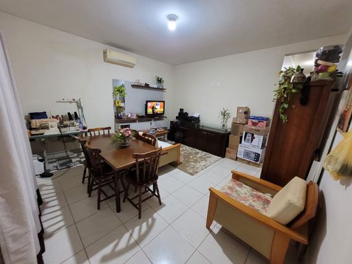 Sala de estar e jantar integradas em ambiente amplo, exibindo conjunto de mesa com cadeiras, estofados de apoio e piso cerâmico uniforme no Bairro Aeroclube, em Porto Velho-RO.