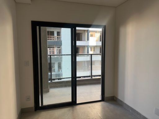 Vista interna do living social em direção à varanda gourmet, destacando o guarda-corpo panorâmico em vidro escuro e perfis metálicos pretos no Bairro Olaria, em Porto Velho-RO.