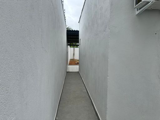 Área de circulação externa com piso em concreto e muros altos, otimizando o isolamento e a privacidade da unidade no Bairro Nova Esperança, em Porto Velho-RO.