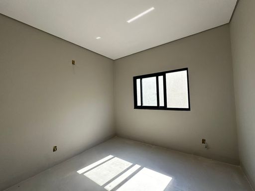 Dormitório privativo com piso em porcelanato claro, paredes em tom neutro com pintura lisa, teto com forro de gesso e tabica perimetral, e janela de correr em alumínio anodizado preto no Bairro Triângulo, em Porto Velho-RO.