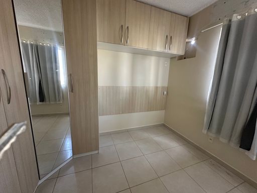Dormitório com roupeiro planejado em tons amadeirados claros, incluindo porta espelhada e módulos superiores para otimização de espaço no Bairro Aeroclube, em Porto Velho-RO.