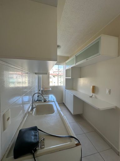 Detalhe da área úmida da cozinha com cuba embutida e armários aéreos com acabamento em vidro, priorizando a organização no Bairro Aeroclube, em Porto Velho-RO.