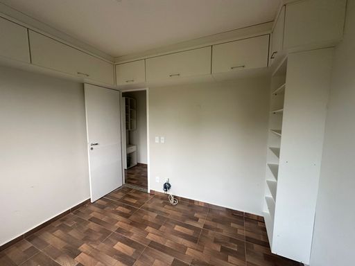 Dormitório com piso em padrão amadeirado, armário planejado superior e nichos laterais, oferecendo praticidade e melhor aproveitamento do espaço no Bairro Novo, Porto Velho/RO.