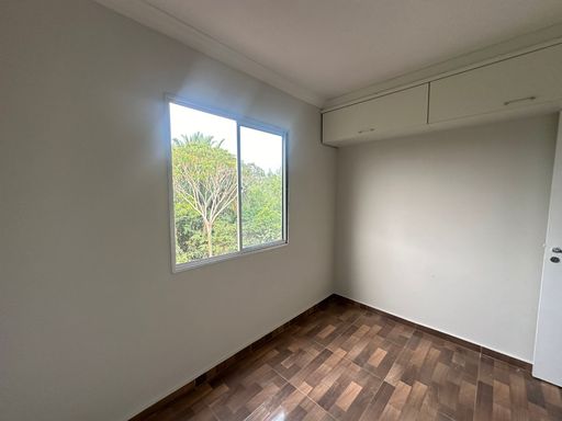 Quarto bem iluminado, com janela para área externa, paredes em tons neutros e piso amadeirado, pronto para diferentes composições de mobiliário.