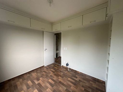 Quarto com piso em padrão amadeirado e armários planejados superiores, otimizando o espaço. Ambiente funcional e agradável, ideal para apartamento prático no Bairro Novo, em Porto Velho/RO.