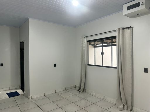 Living interno com piso cerâmico em tons claros, pintura em bom estado e ampla janela para ventilação natural no Bairro Nova Esperança, em Porto Velho-RO.