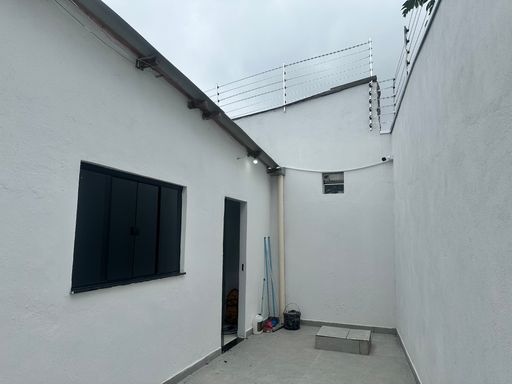 Corredor lateral de serviço com janelas em alumínio escuro e iluminação externa instalada, garantindo segurança noturna no Bairro Nova Esperança, em Porto Velho-RO.