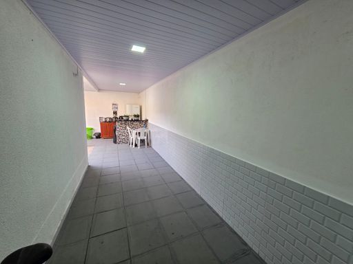 Corredor de acesso interno do Condomínio Dália no bairro Novo, Porto Velho, com piso cerâmico e área coberta.
