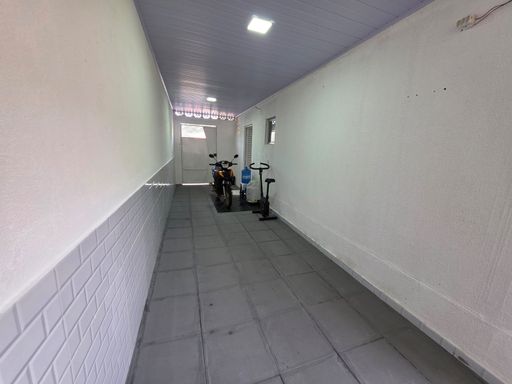 Área de circulação coberta do Condomínio Dália em Porto Velho, com corredor amplo, piso cerâmico e iluminação no teto.