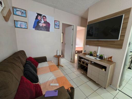Sala de estar do imóvel no Condomínio Dália em Porto Velho, com sofá, painel para TV e ambiente integrado.