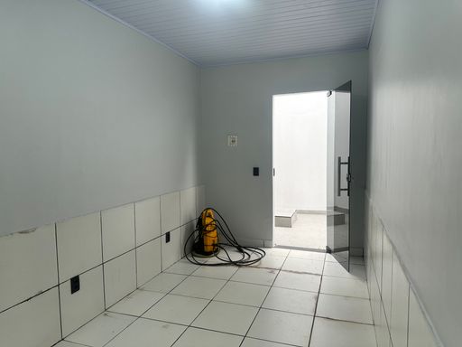 Área de transição interna com revestimento cerâmico em meia parede e porta em vidro temperado, facilitando a manutenção no Bairro Nova Esperança, em Porto Velho-RO.