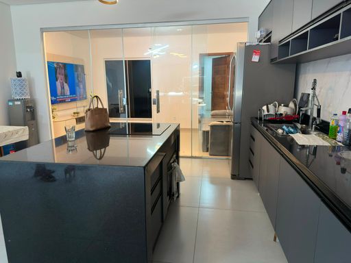 Detalhe da ilha técnica centralizada com cooktop embutido e marcenaria planejada em tom grafite escuro, ressaltando o conceito moderno e funcional no Bairro Aponiã, em Porto Velho-RO.